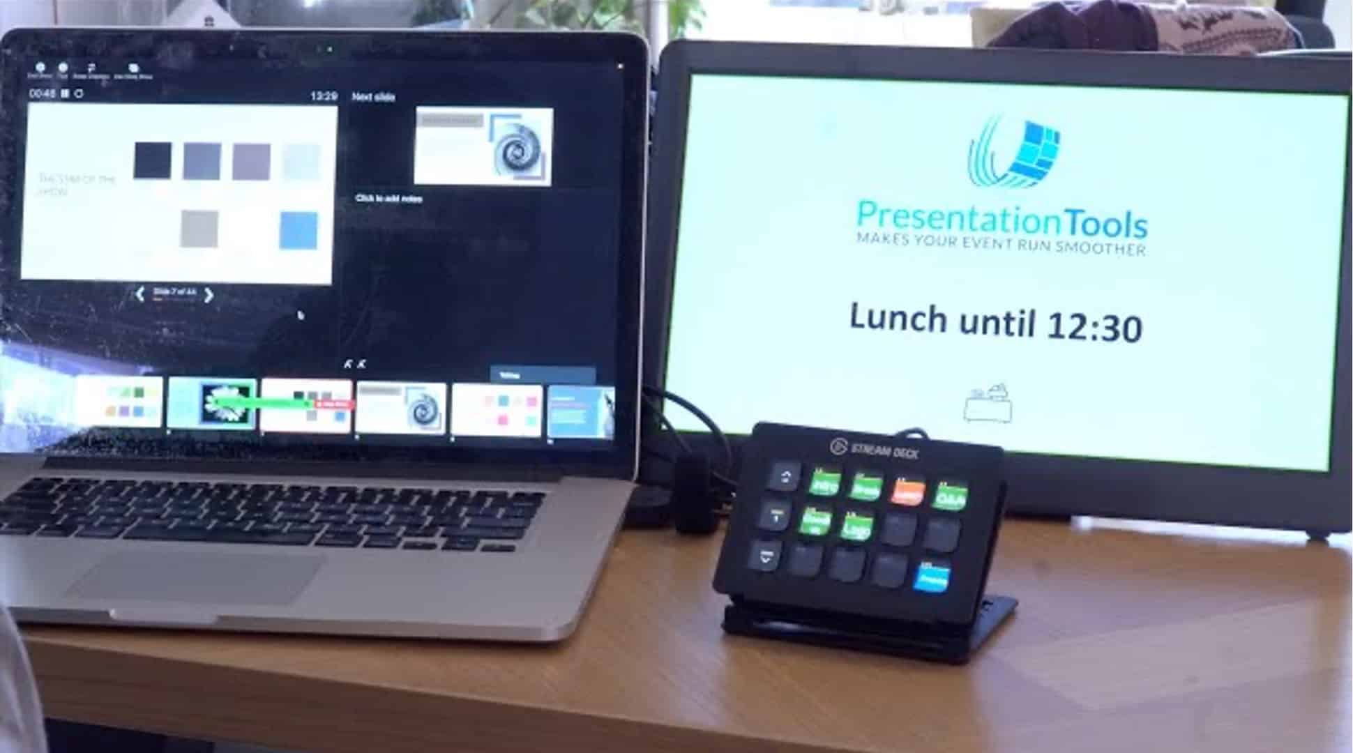 A laptop displaying a software interface with presentation options, next to a monitor showing 'Lunch until 12:30' with the logo of 'PresentationTools.' A control pad with buttons is also visible on the desk.