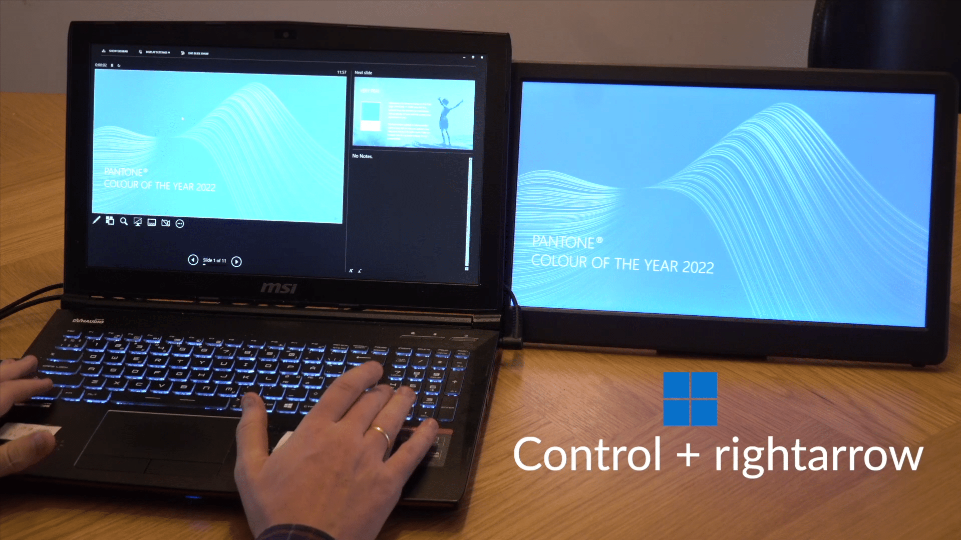 A person using a laptop with a backlit keyboard, displaying a presentation about Pantone's Color of the Year 2022. A second screen shows the same content, with text indicating the keyboard shortcut 'Control + right arrow'.